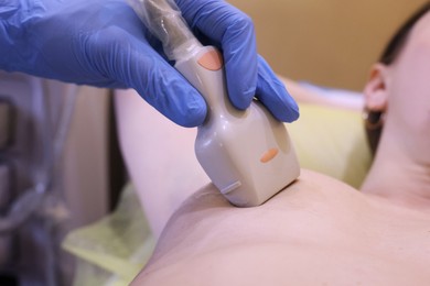 Mammologist conducting ultrasound examination of woman's breast in clinic, closeup