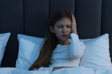 Little girl suffering from headache in bed at night