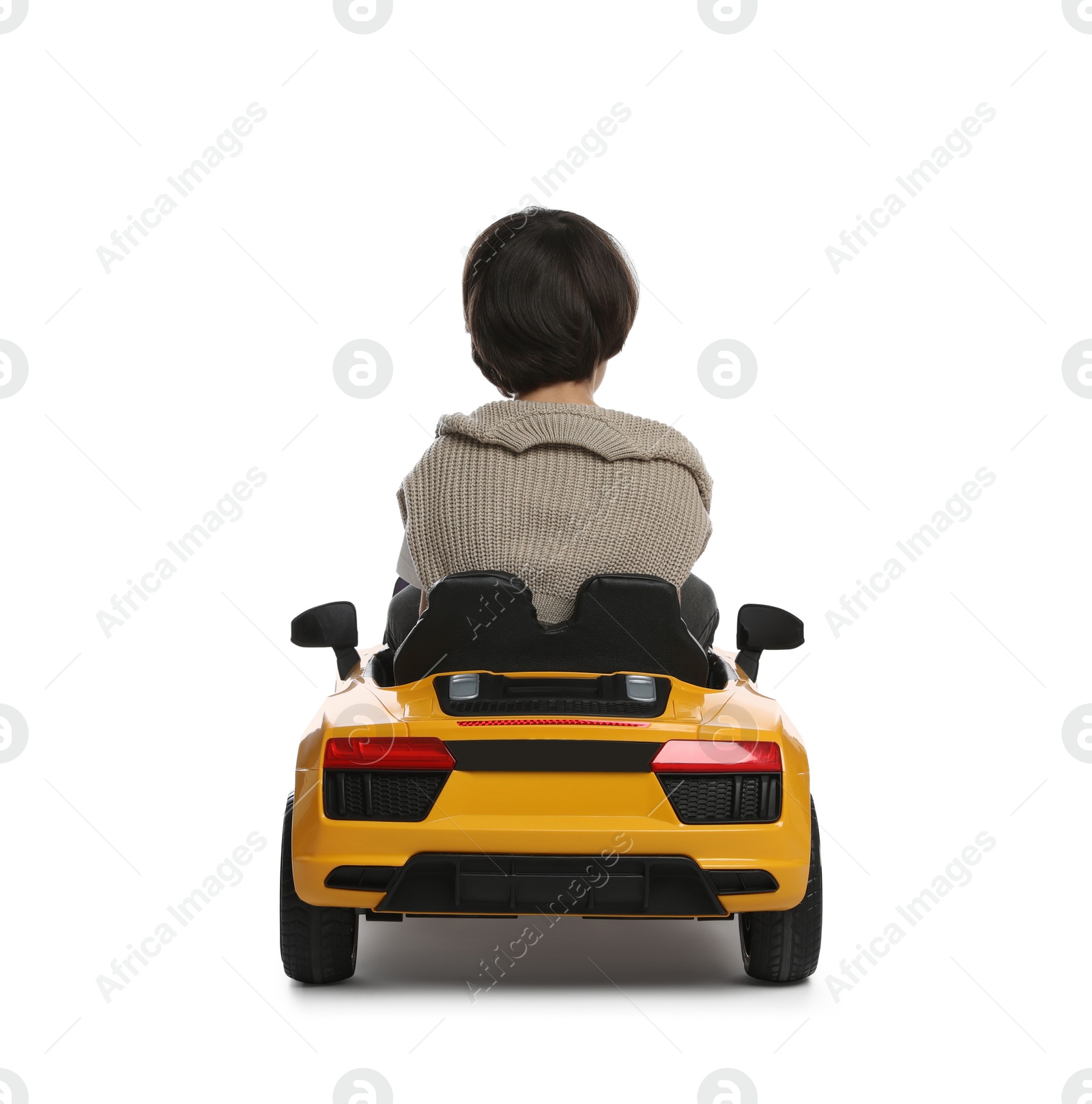 Photo of Cute little boy driving children's electric toy car on white background, back view