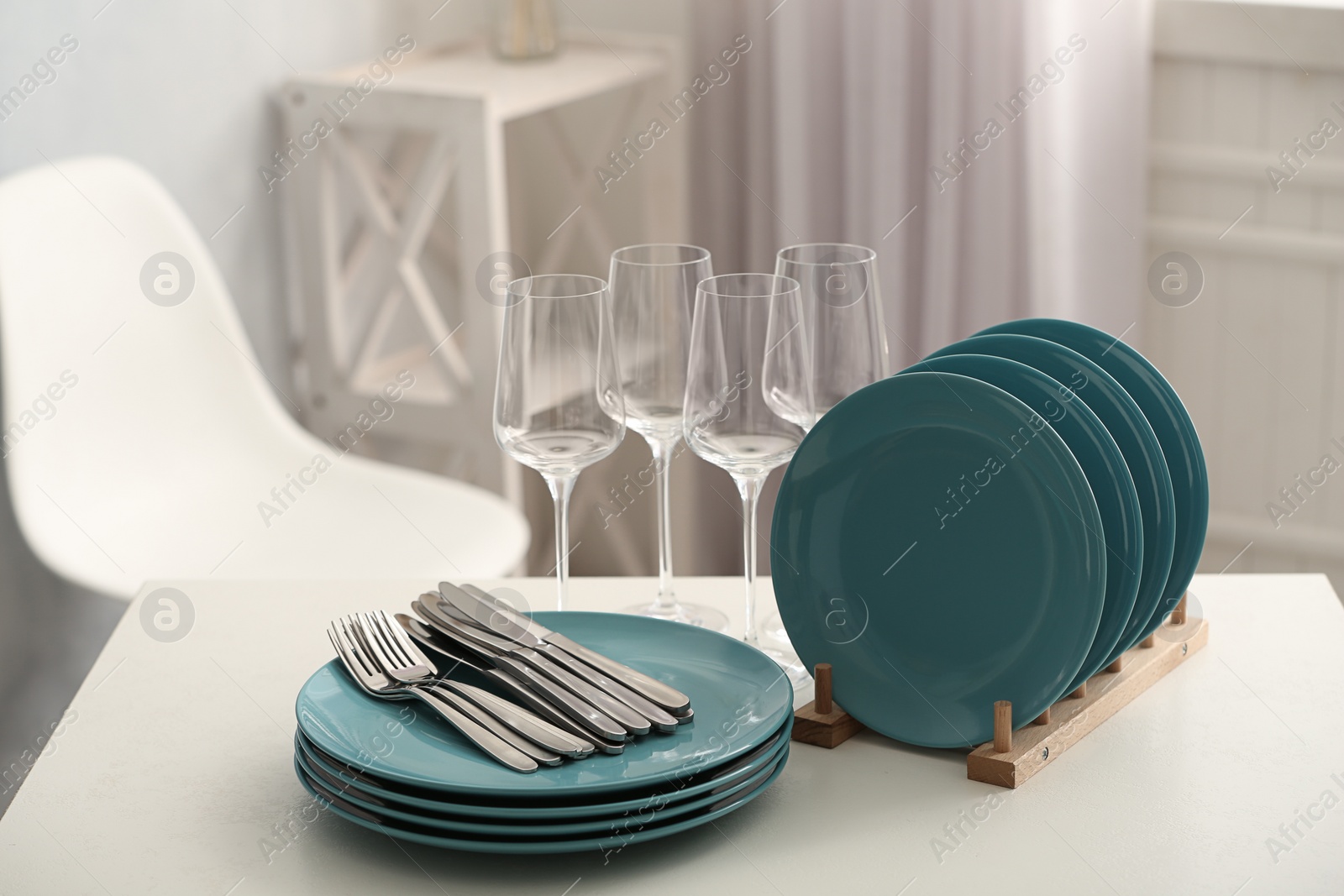 Photo of Set of clean dishes, cutlery and wineglasses on white table indoors