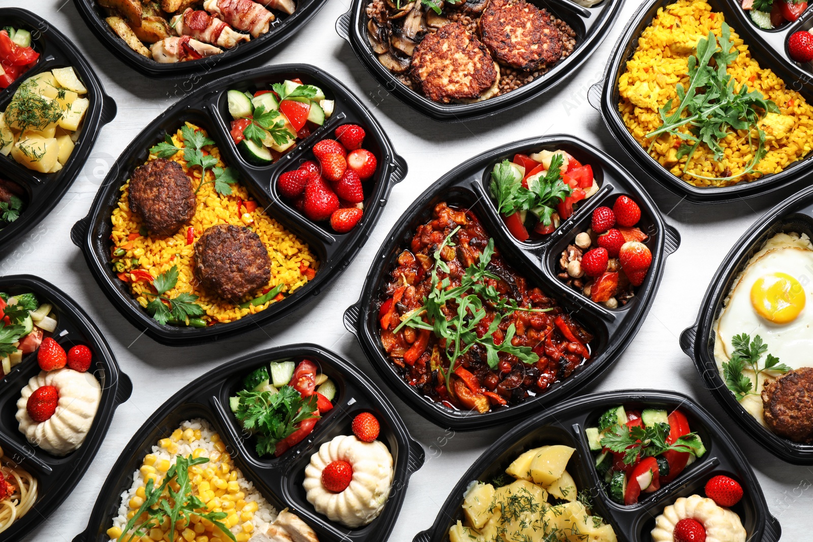 Photo of Lunchboxes with different meals on white table, flat lay. Healthy food delivery