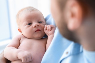 Photo of Father holding his cute newborn baby at home, closeup