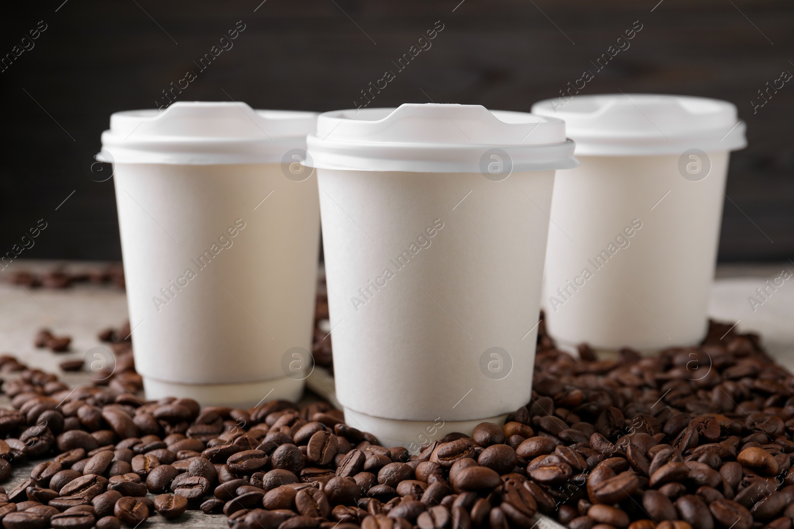 Photo of Coffee to go. Paper cups and roasted beans on table, closeup