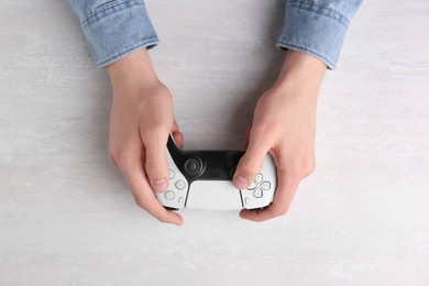 Man using wireless game controller at white table, top view