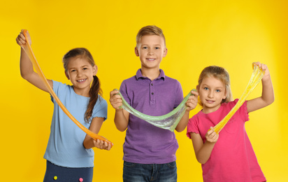 Photo of Happy children with slime on yellow background