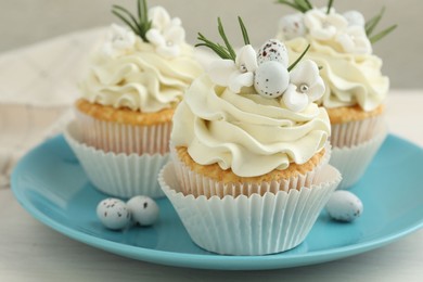 Photo of Tasty Easter cupcakes with vanilla cream on light wooden table, closeup