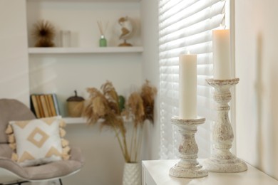 Photo of Beautiful wooden candlesticks on white table in room, space for text
