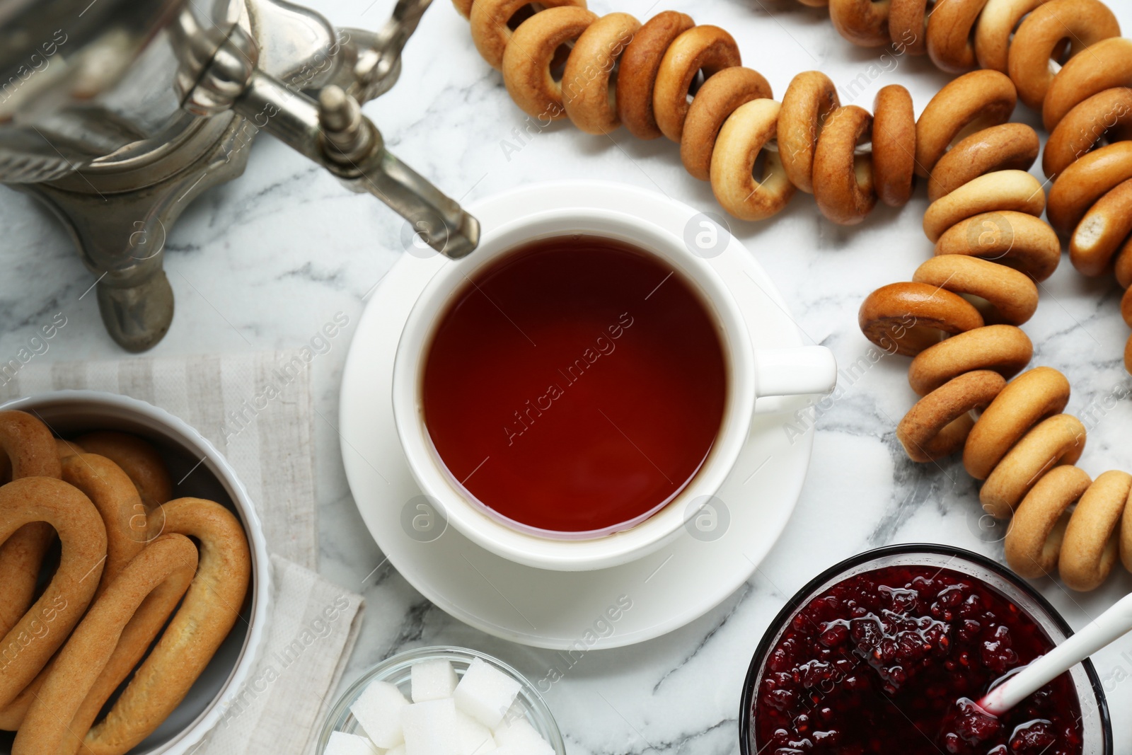 Photo of Flat lay composition with delicious ring shaped Sushki (dry bagels) and cup of tea on white marble table