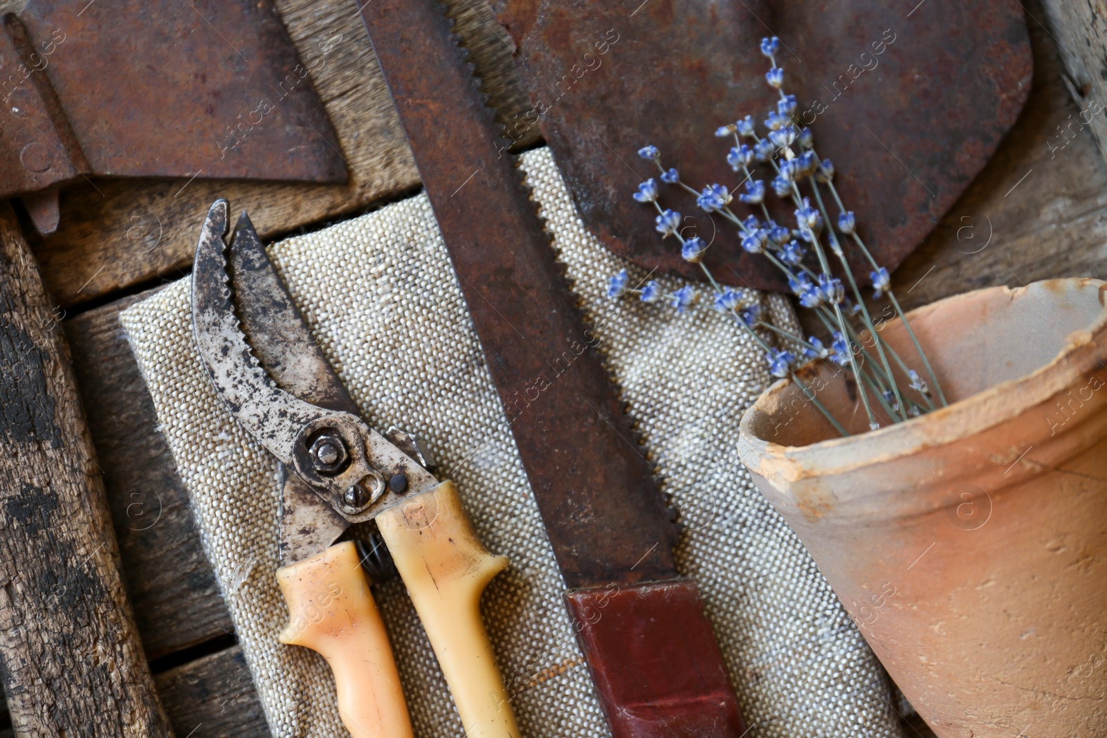 Photo of Flat lay composition with old secateurs and other gardening tools on wooden table