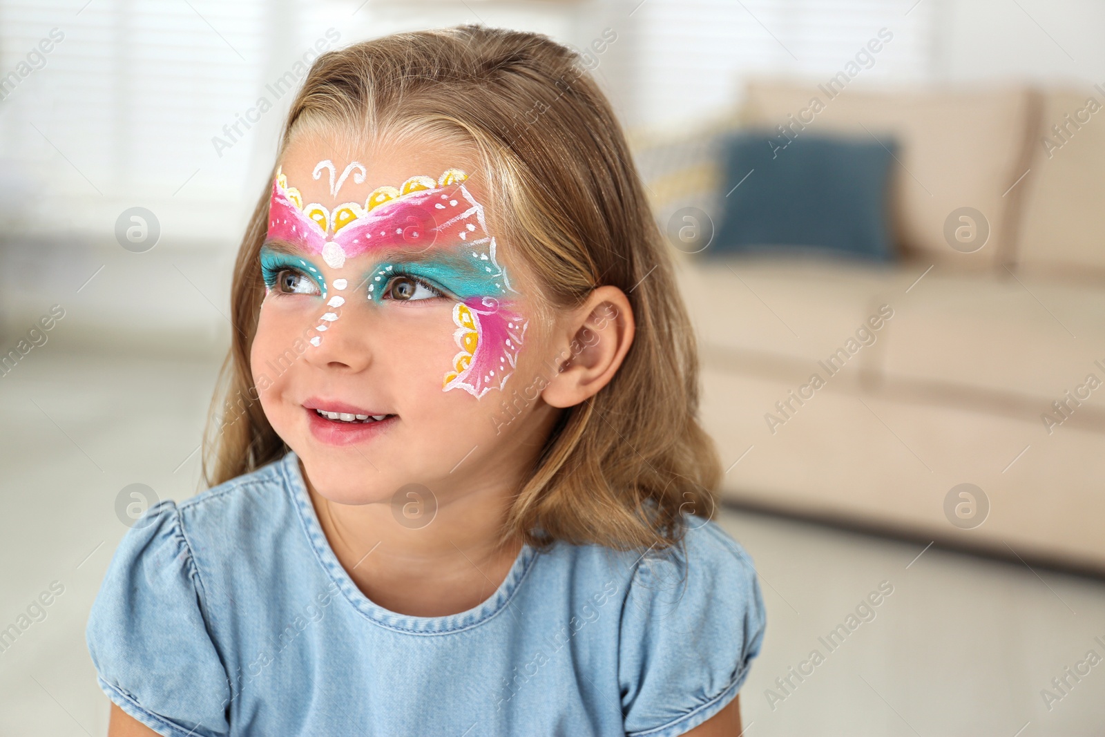 Photo of Cute little girl with face painting indoors