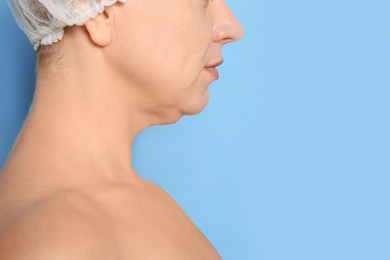 Mature woman with double chin on blue background, closeup. Space for text