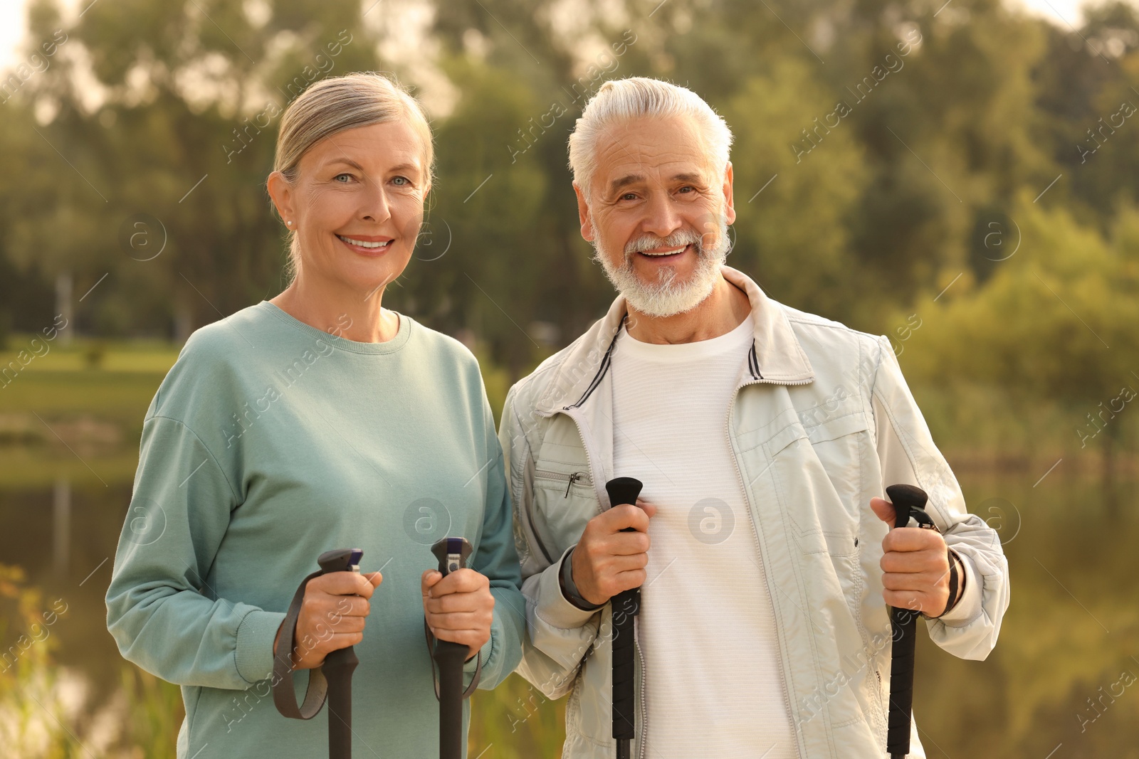 Photo of Senior man and woman with Nordic walking poles outdoors