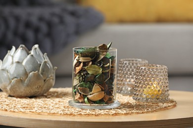 Glass jar with aromatic potpourri of dried flowers and different decor on wooden table indoors