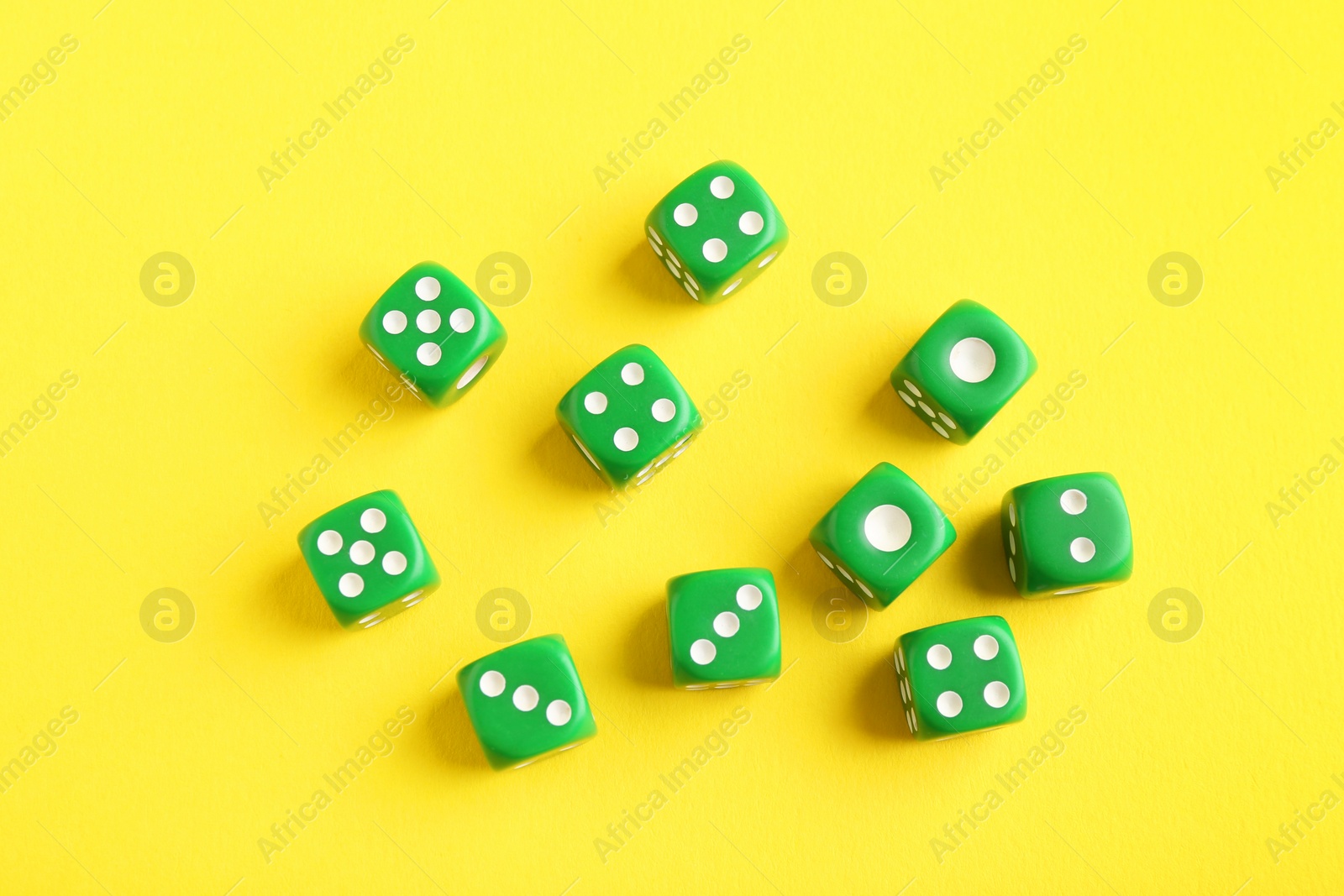 Photo of Many green game dices on yellow background, flat lay