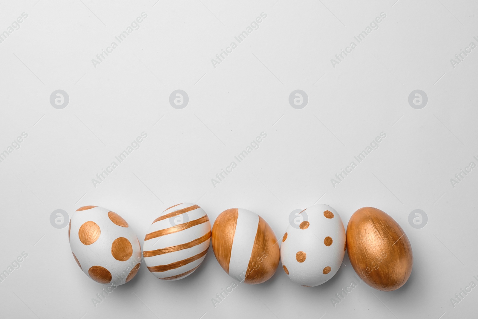 Photo of Set of traditional Easter eggs decorated with golden paint on white background, top view. Space for text