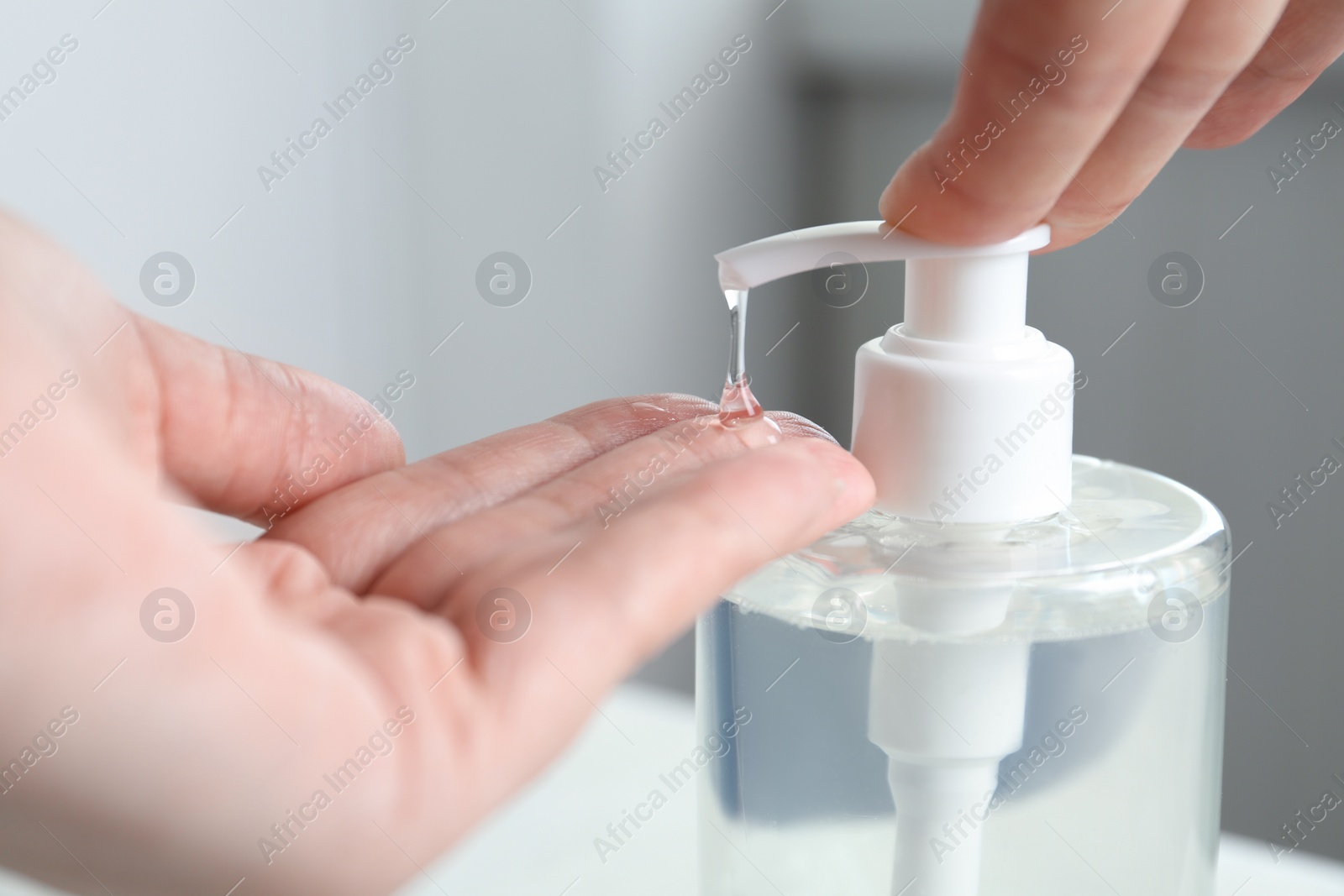 Photo of Woman applying antiseptic gel on hand indoors, closeup