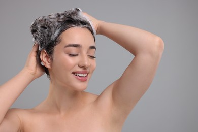 Photo of Beautiful happy woman washing hair on grey background