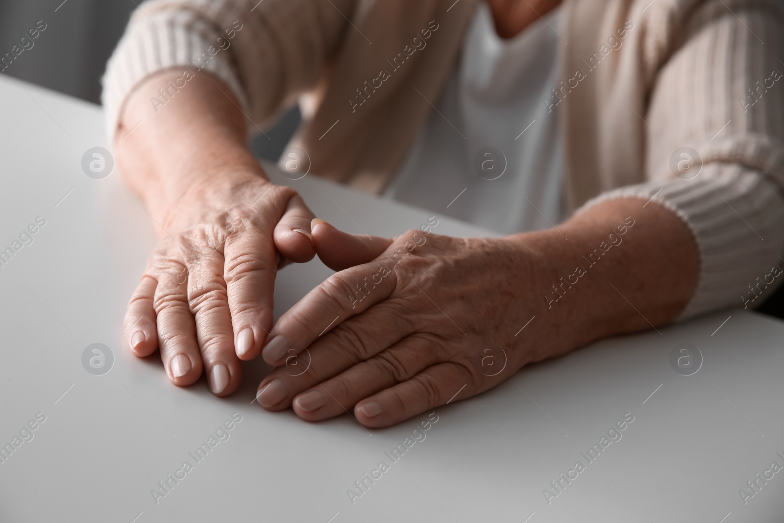 Photo of Elderly woman at white table, closeup view