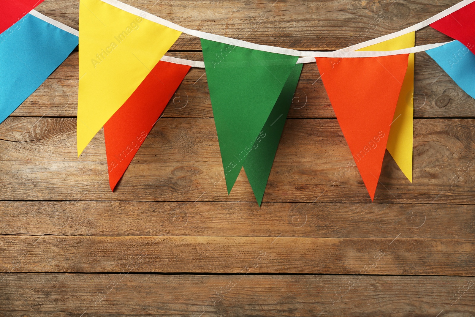 Photo of Buntings with colorful triangular flags hanging on wooden wall. Space for text