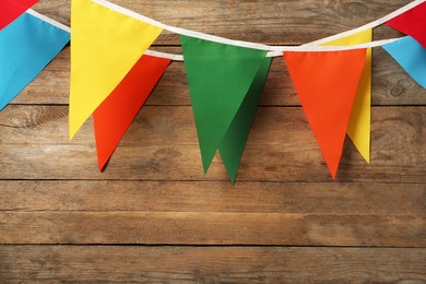 Buntings with colorful triangular flags hanging on wooden wall. Space for text