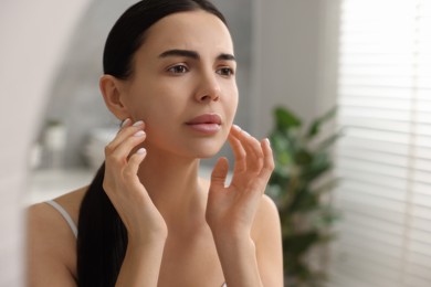 Photo of Woman with dry skin looking at mirror indoors