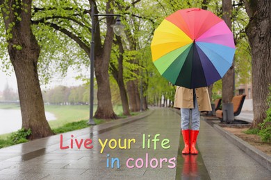 Image of Live your life in colors, affirmation. Woman with rainbow umbrella walking in park on spring day