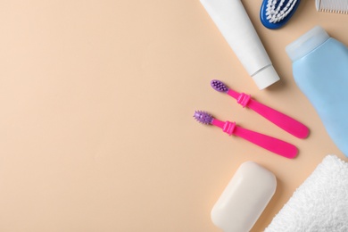 Flat lay composition with baby toothbrushes, toiletries and space for text on color background