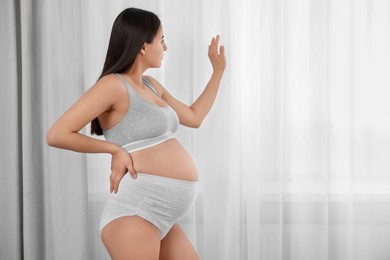Photo of Beautiful pregnant woman in comfortable maternity underwear indoors, space for text