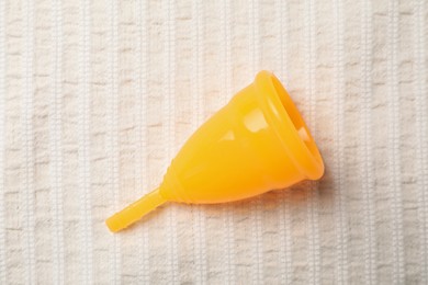 Menstrual cup on light fabric, top view