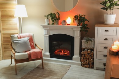 Photo of Stylish fireplace near comfortable armchair in cosy living room. Interior design