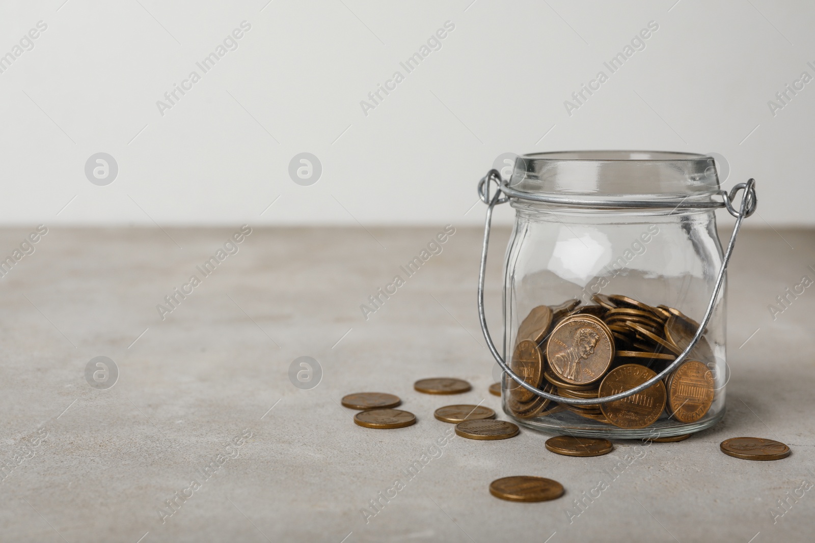 Photo of Glass jar with coins on grey table, space for text