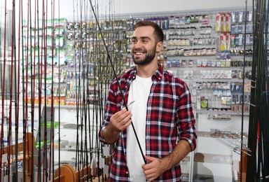 Photo of Man choosing fishing rod in sports shop