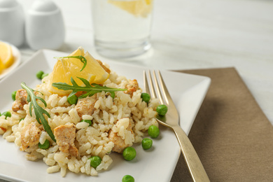 Delicious chicken risotto with lemon on table, closeup