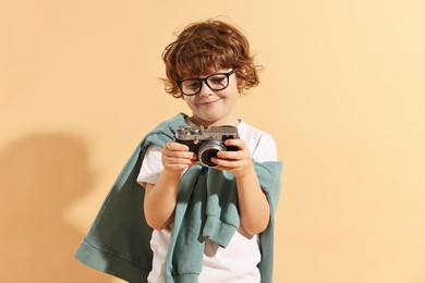 Fashion concept. Stylish boy with vintage camera on pale orange background