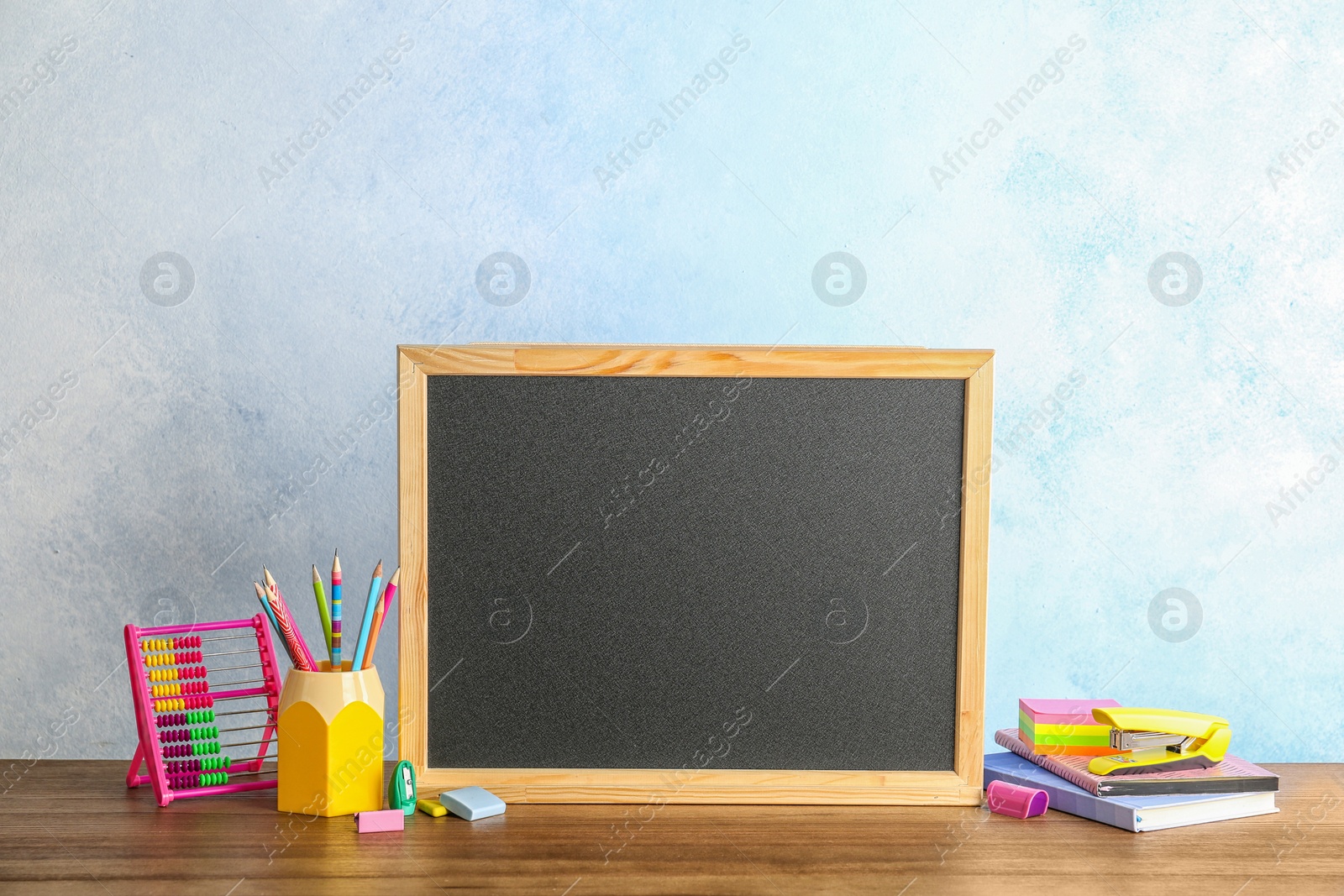 Photo of Small chalkboard and different school stationery on table