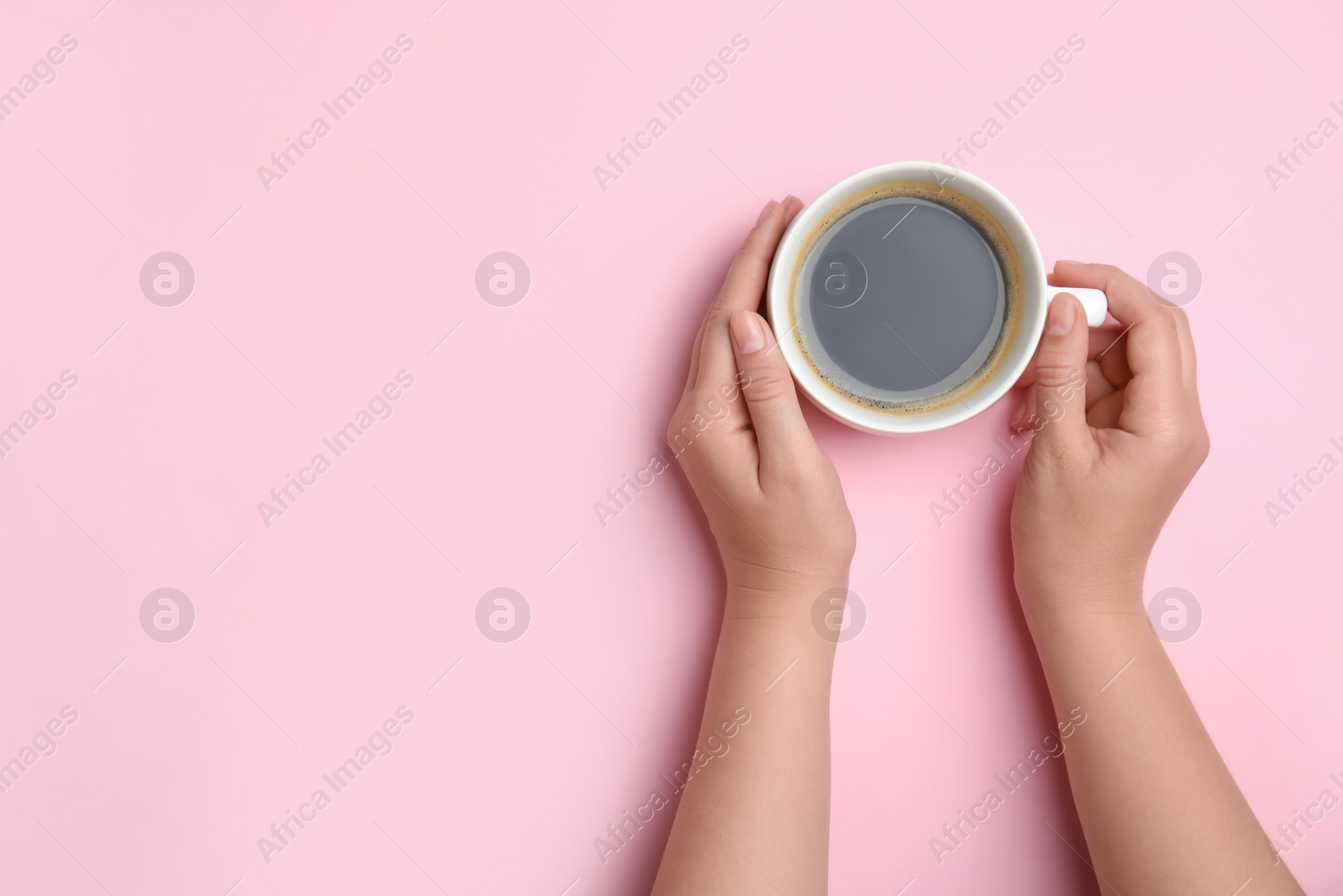 Photo of Woman with cup of coffee on light pink background, top view. Space for text