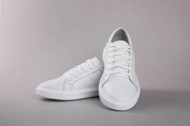 Photo of Pair of stylish white sneakers on grey background