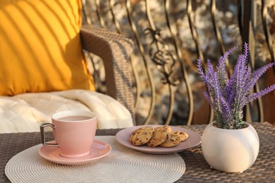 Photo of Cup with tasty cocoa and cookies on rattan table at balcony