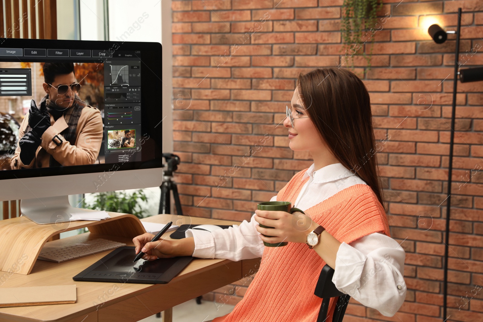 Photo of Professional retoucher working on graphic tablet at desk in office