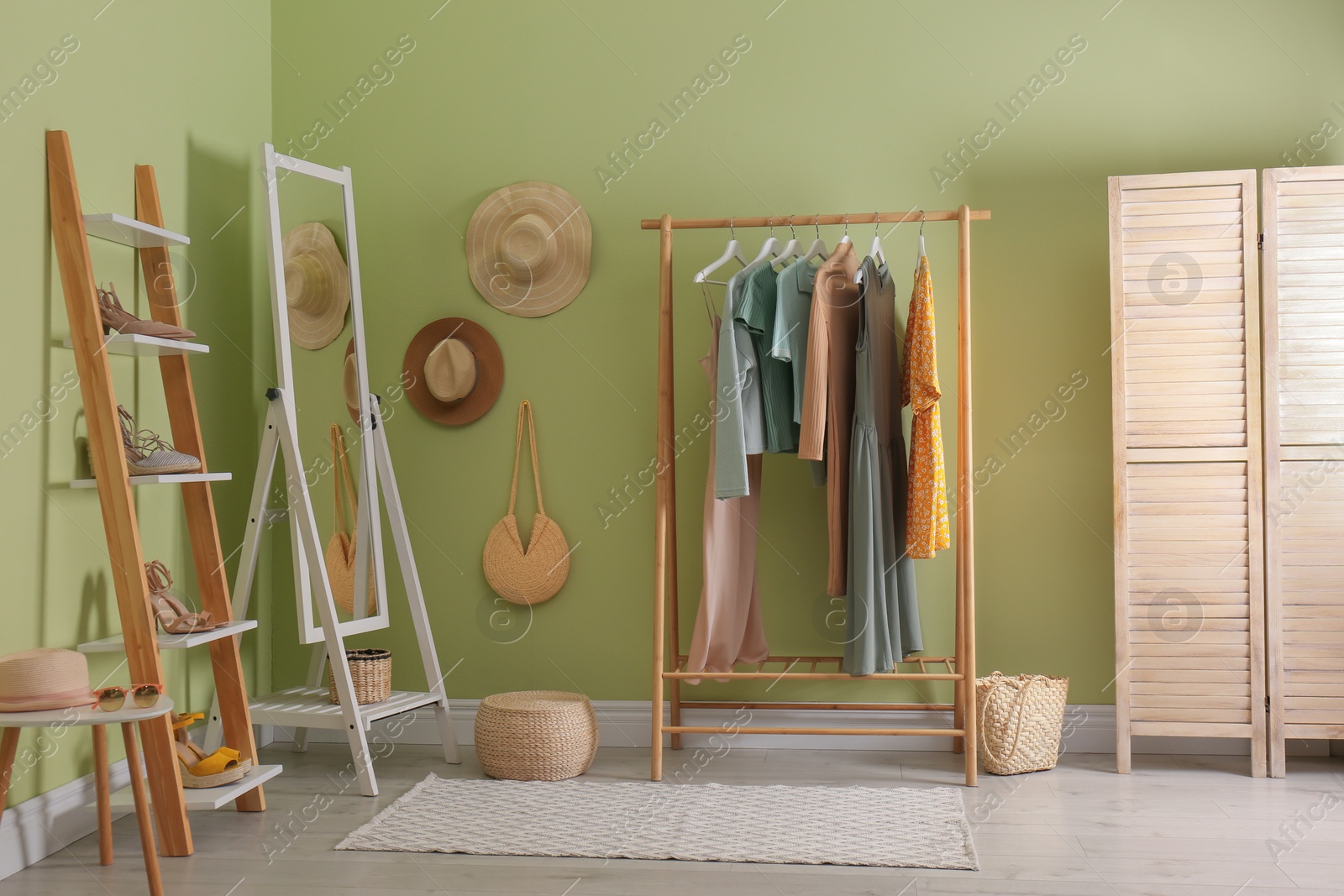 Photo of Modern dressing room interior with clothing rack and mirror near light green wall