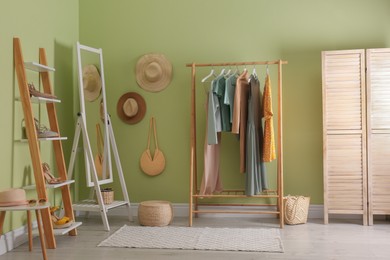 Modern dressing room interior with clothing rack and mirror near light green wall