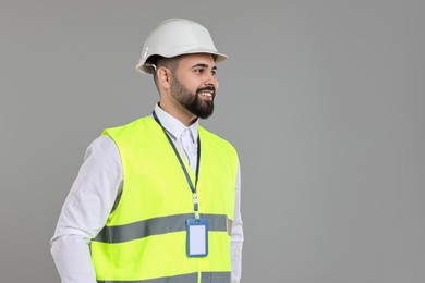 Photo of Engineer with hard hat and badge on grey background, space for text