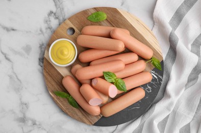 Photo of Delicious boiled sausages, sauce and basil on white marble table, top view