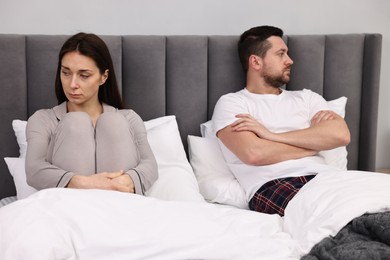 Photo of Offended couple ignoring each other after quarrel in bed. Relationship problems