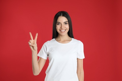 Photo of Woman showing number two with her hand on red background