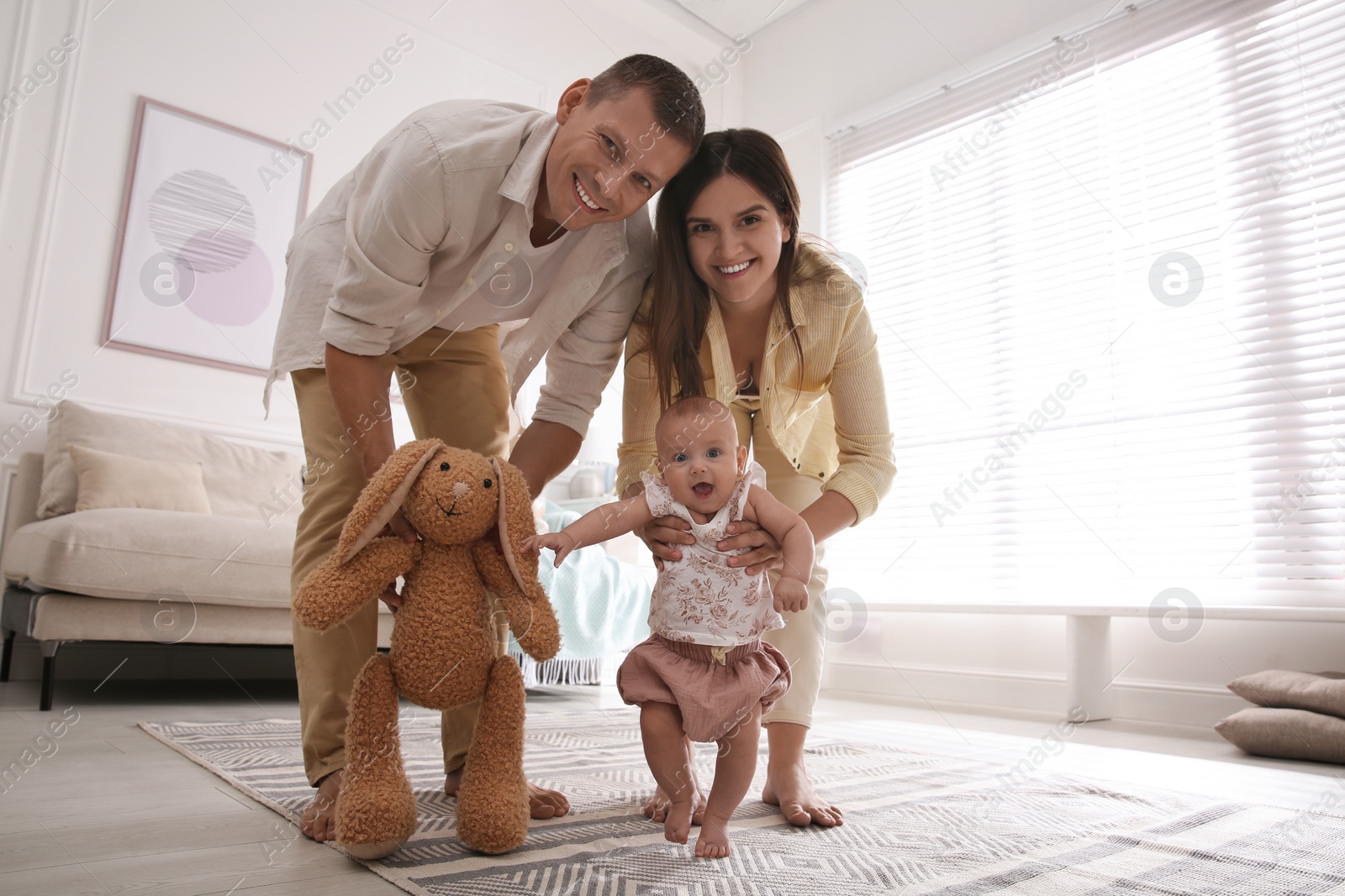 Photo of Cute little baby doing first steps with parents' help at home