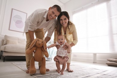 Cute little baby doing first steps with parents' help at home