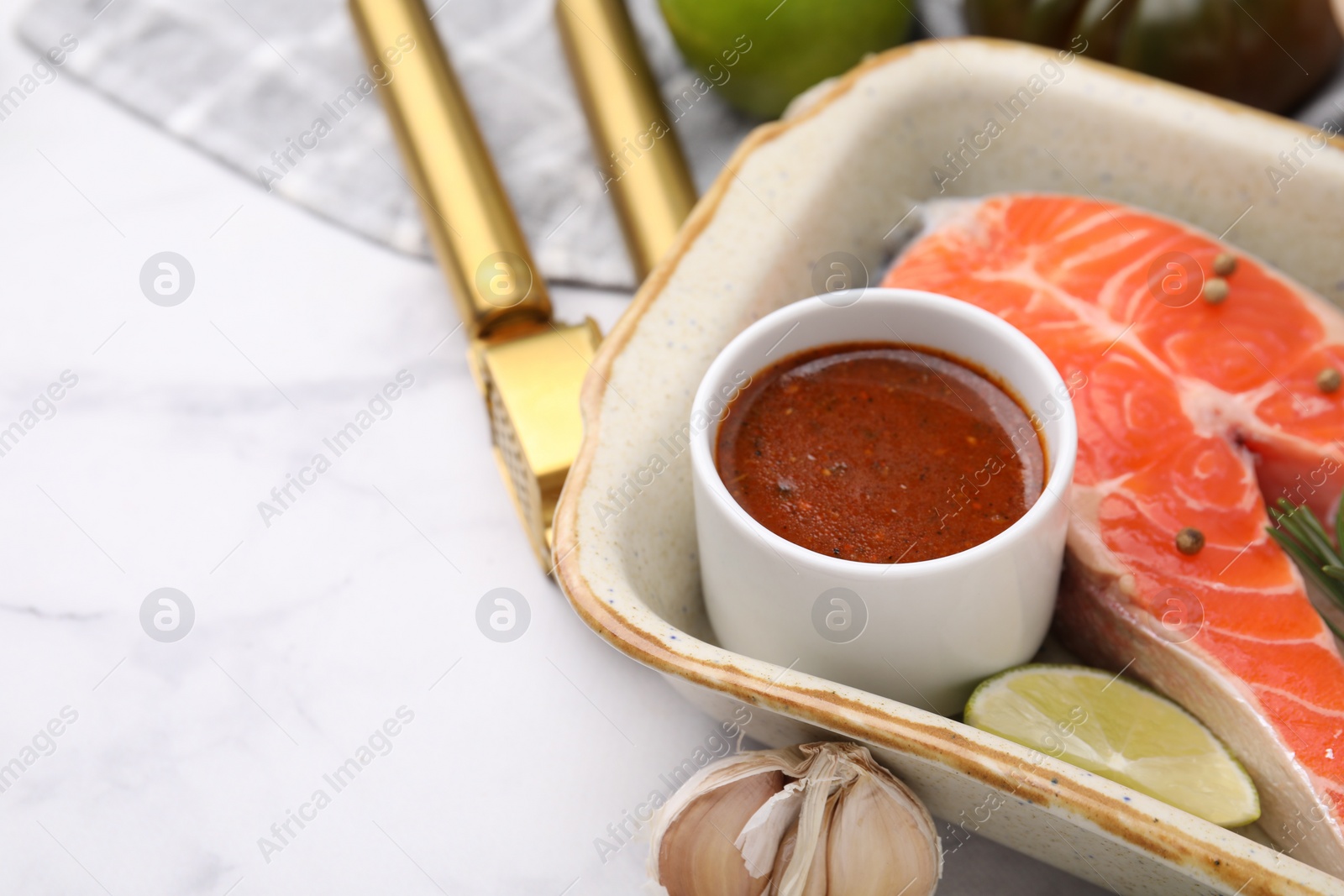 Photo of Fresh marinade, fish and lime in baking dish on light table, closeup. Space for text