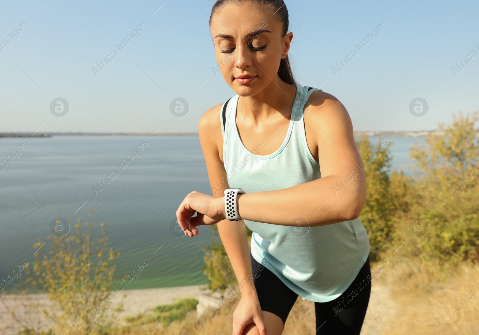 Photo of Woman checking modern smart watch during training outdoors