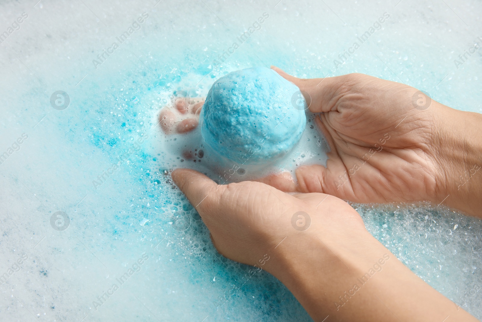 Photo of Woman holding bomb in color water, closeup